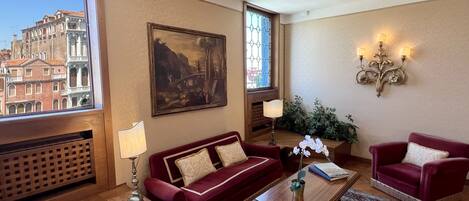 A living room with a red sofa, a wooden coffee table, and a painting on the wall.