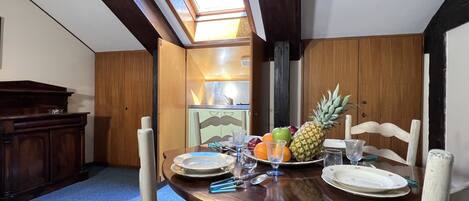 Comedor con una mesa de madera dispuesta para cuatro, una piña y diversas frutas.