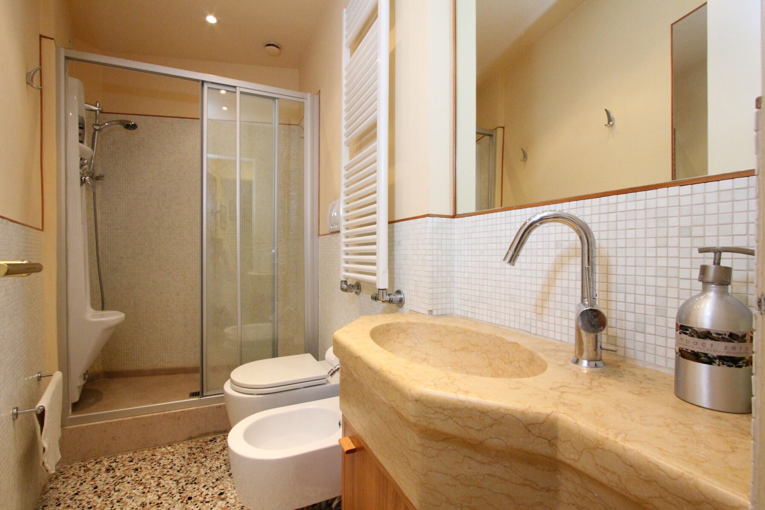 A bathroom with a shower, toilet, sink, and mirror.