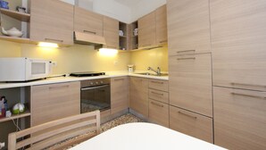 Cozinha compacta com armários de madeira, micro-ondas, forno e pia.