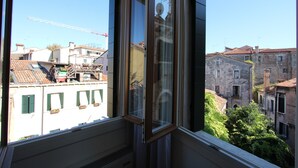 Vista da janela sobre uma paisagem urbana com edifícios, uma grua e céu claro.
