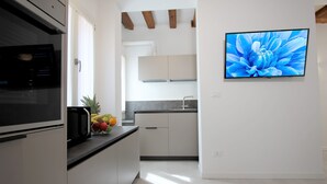 A modern kitchen with white cabinets, a black microwave, and a fruit bowl on the counter.