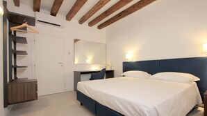 A bedroom with a bed, bedside tables, a desk, a chair, a wardrobe, and a mirror.
