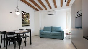 A modern living space with a dining area, a sofa, and a kitchen.