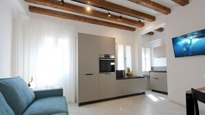 A modern kitchen with a built-in oven and microwave, a dining area with a table and chairs, and a living room with a sofa and a lamp.