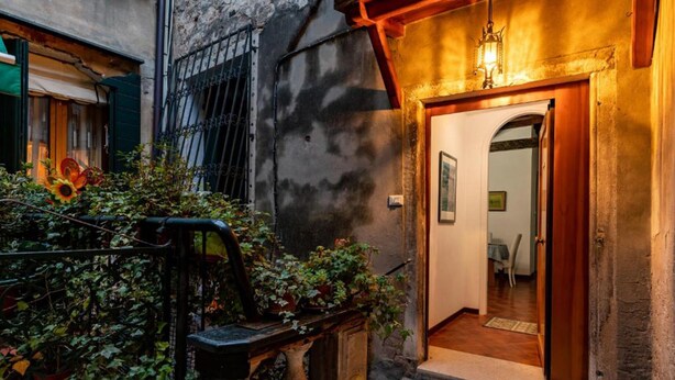 A narrow alleyway with a wooden door leading to a room with a mirror and a small table.
