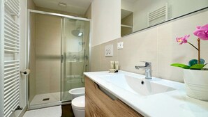 A modern bathroom with a glass shower enclosure, a white sink with a mirror above, and a potted orchid on the counter. - San Marco Canal View (200m from St. Mark´s Square) (Venecia)