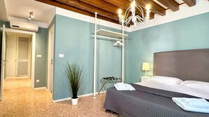 A bedroom with a bed, a nightstand, a lamp, a hanging light fixture, a plant, and a drying rack. - San Marco Canal View (200m from St. Mark´s Square) (Venecia)