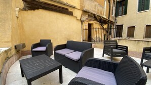 A courtyard with wicker furniture, including sofas and a table, and a staircase leading to an upper level. - Manin Terrace (200m from St Mark´s Square) (Venecia)