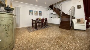 A spacious living area with a dining table, chairs, a sofa, a staircase, and a kitchen area. - Manin Terrace (200m from St Mark´s Square) (Venecia)