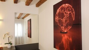 A modern room with a wooden ceiling, a black bench, a white vase with an orchid, and a large globe artwork on the wall.