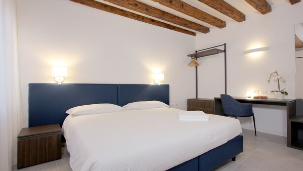 A bedroom with a large bed, bedside tables, a desk with a chair, and a hanging light fixture. - Splash Art (Residence Modern Art) (Venecia)