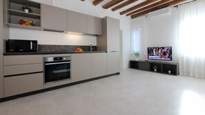 A modern kitchen with built-in appliances, a flat-screen TV, and a dining area with a table and chairs.