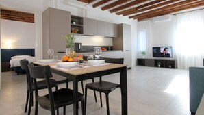 A modern living room with a dining table set for four, a kitchen in the background, and a television on a stand. - Splash Art (Residence Modern Art) (Venecia)