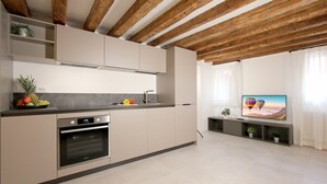 Une cuisine moderne dotée d’un four encastré, d’un grand îlot central et d’un téléviseur à écran plat fixé au mur.