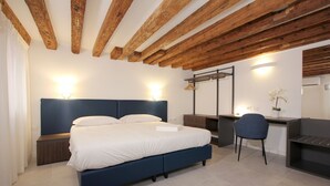 Une chambre à coucher comprenant un lit, des tables de chevet, un bureau, une chaise et un miroir.