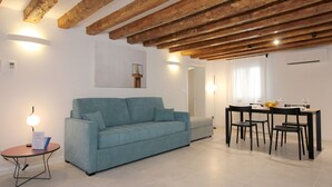 Un salon moderne comprenant un canapé, une table à manger avec des chaises et une petite table ronde avec une lampe.