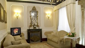 Un salón tradicional con dos sillones, una chimenea y un televisor que muestra el canal BBC News.