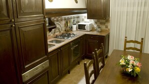 Una cocina con armarios de madera, estufa a gas, microondas y pileta.