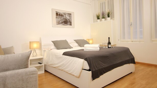 A modern bedroom with a bed, bedside tables, a nightstand, a window with curtains, and a wall-mounted air conditioner. - San Marco Gallery (80m from St Mark´s Square) (Venecia)