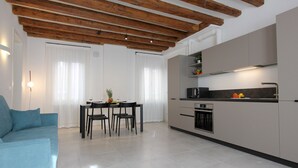 A modern kitchen with a dining area, featuring a wooden ceiling, white walls, and grey cabinets. - Residence Modern Art 3 (Venecia)