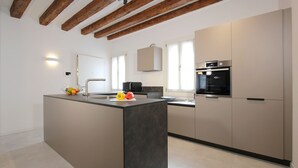 A modern kitchen with a central island, built-in appliances, and a wooden ceiling. - Residence Modern Art 3 (Venecia)
