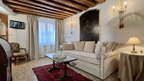 Ein Wohnzimmer mit Sofa, Couchtisch, Fernseher und einer Kronleuchter.