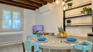 A dining area with a round table, blue chairs, and a fruit bowl.