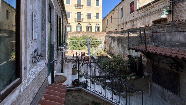 A narrow alleyway with a staircase leading to a building with a balcony.