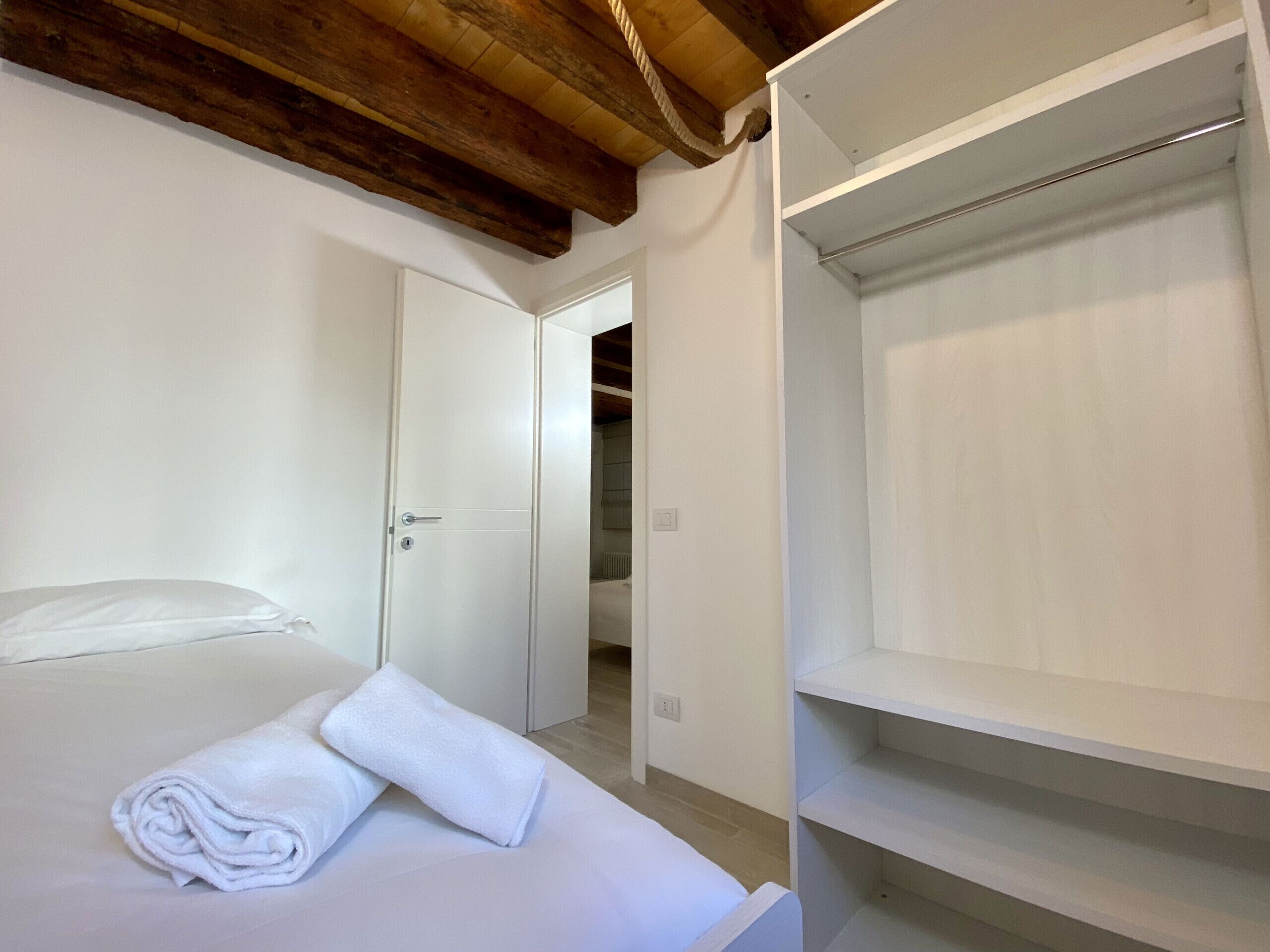 Une chambre à coucher avec un lit, une armoire blanche et un plafond en bois.