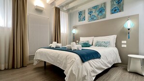 A hotel room with a large bed, two bedside lamps, a small table, and artwork on the wall. - Acquamarina Terrace (Historical Center) (Venecia)