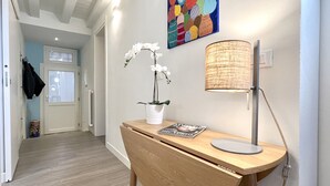 A hallway with a wooden desk, a white orchid, a lamp, and a colorful painting on the wall. - Acquamarina Terrace (Historical Center) (Venecia)