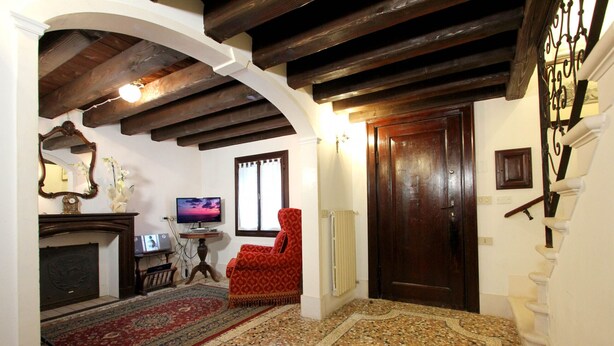 A room with a fireplace, a television, a red armchair, and a wooden staircase. - Apartment Marin Venetian Style (Venecia)