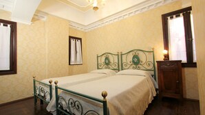 A room with two single beds, a wooden nightstand, a chandelier, and patterned wallpaper. - Apartment Marin Venetian Style (Venecia)