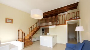 A spacious living area with a wooden staircase, a white kitchen island, and a blue sofa. - Apartment Grand Canal View (with lift) (Venecia)