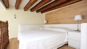 A bedroom with a wooden ceiling, a bed with white bedding, a nightstand with a lamp, and a wooden floor. - Apartment Grand Canal View (with lift) (Venecia)