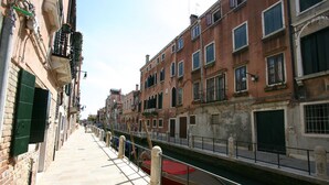 Un canal étroit, bordé de bâtiments des deux côtés, avec des balcons et des fenêtres.