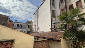 Une rue étroite, bordée de bâtiments des deux côtés, avec un toit recouvert de tuiles et un palmier au premier plan.
