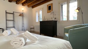 Une chambre à coucher avec un lit, une commode, un radiateur, une fenêtre et une lampe.