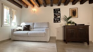 Un salon avec un canapé gris, un meuble en bois et un lustre.
