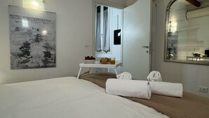 A hotel room with a bed, a small table with breakfast items, a mirror, and a wall with a framed artwork.