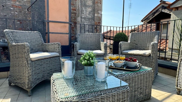 A balcony with wicker furniture, a glass table, and a tray with fruits and drinks.