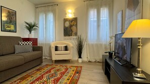 A living room with a sofa, armchair, TV, lamp, and decorative items.
