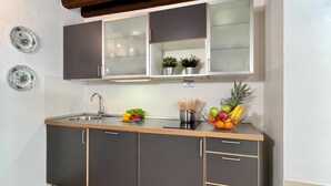 A kitchen with dark cabinets, a stainless steel sink, and a fruit bowl on the counter. - Gelsomino Garden (Residence Flowery) (Venecia)