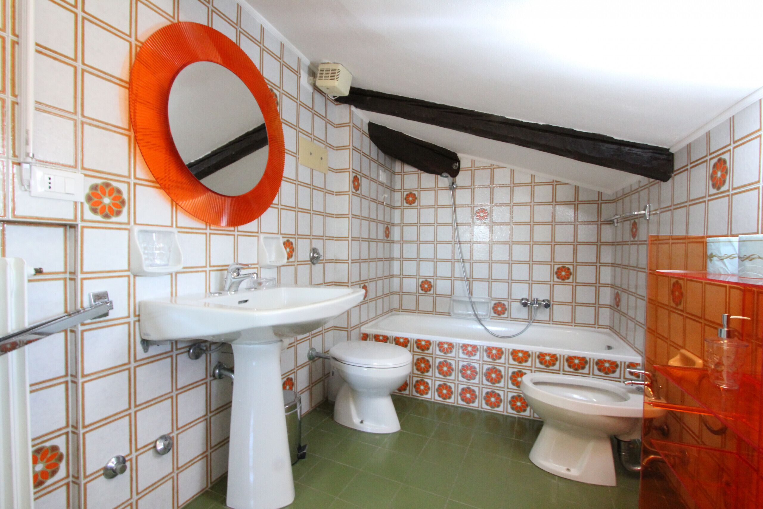 A bathroom with a sink, toilet, and bathtub, featuring patterned tiles and a mirror.