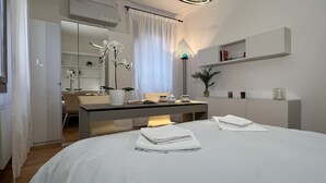 Un dormitorio moderno con cama, mesitas de noche, un escritorio y un armario.