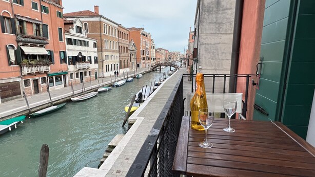 Un balcón con vistas a un canal, barcos y edificios.