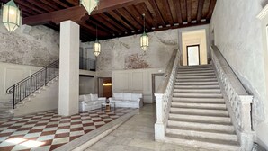 A spacious lobby with a checkered floor, a staircase, and a seating area with white sofas.