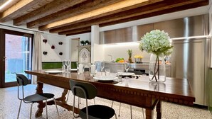 A modern kitchen with a wooden island, stainless steel appliances, and a view to the outside.