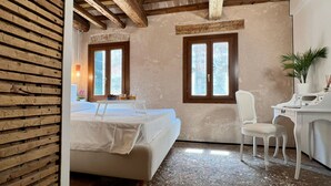 Une chambre à coucher avec un lit, deux fenêtres, un bureau et une chaise.